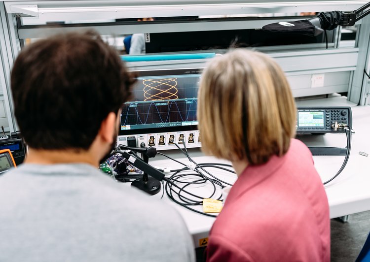 two researchers in front of a screen with different graphs