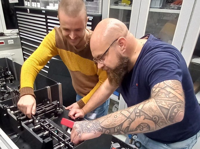 Matteo im Büro mit einem Kollegen vor einem Versuchsaufbau