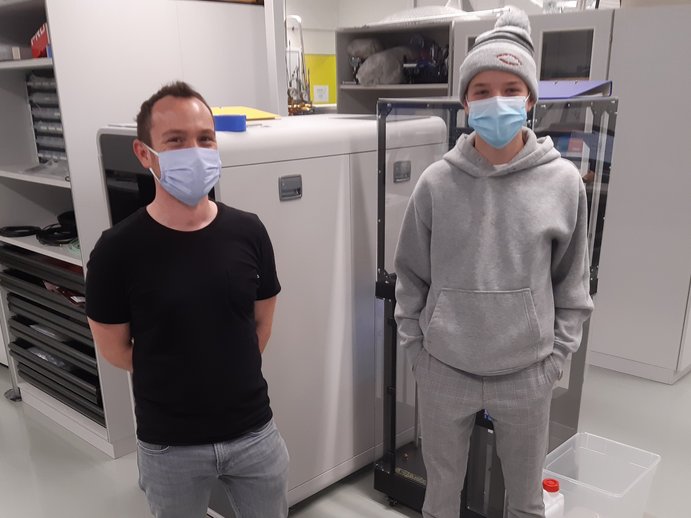 A scientist and a teenage boy are standing in a lab