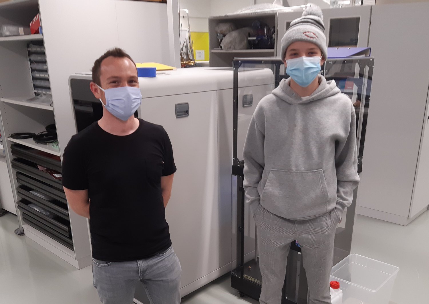 A scientist and a teenage boy are standing in a lab