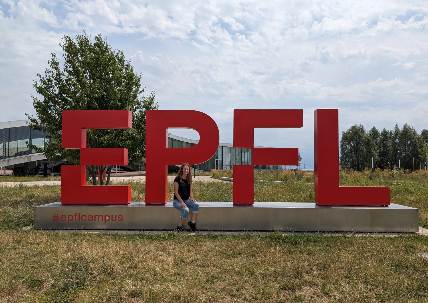 Blonde Frau vor dem physischen Logo der EPFL
