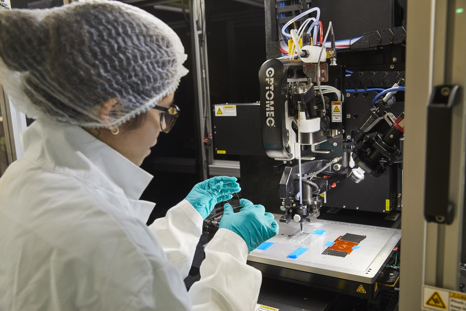 Emily B. in protective clothing, working with the Aerosol Jet Printer