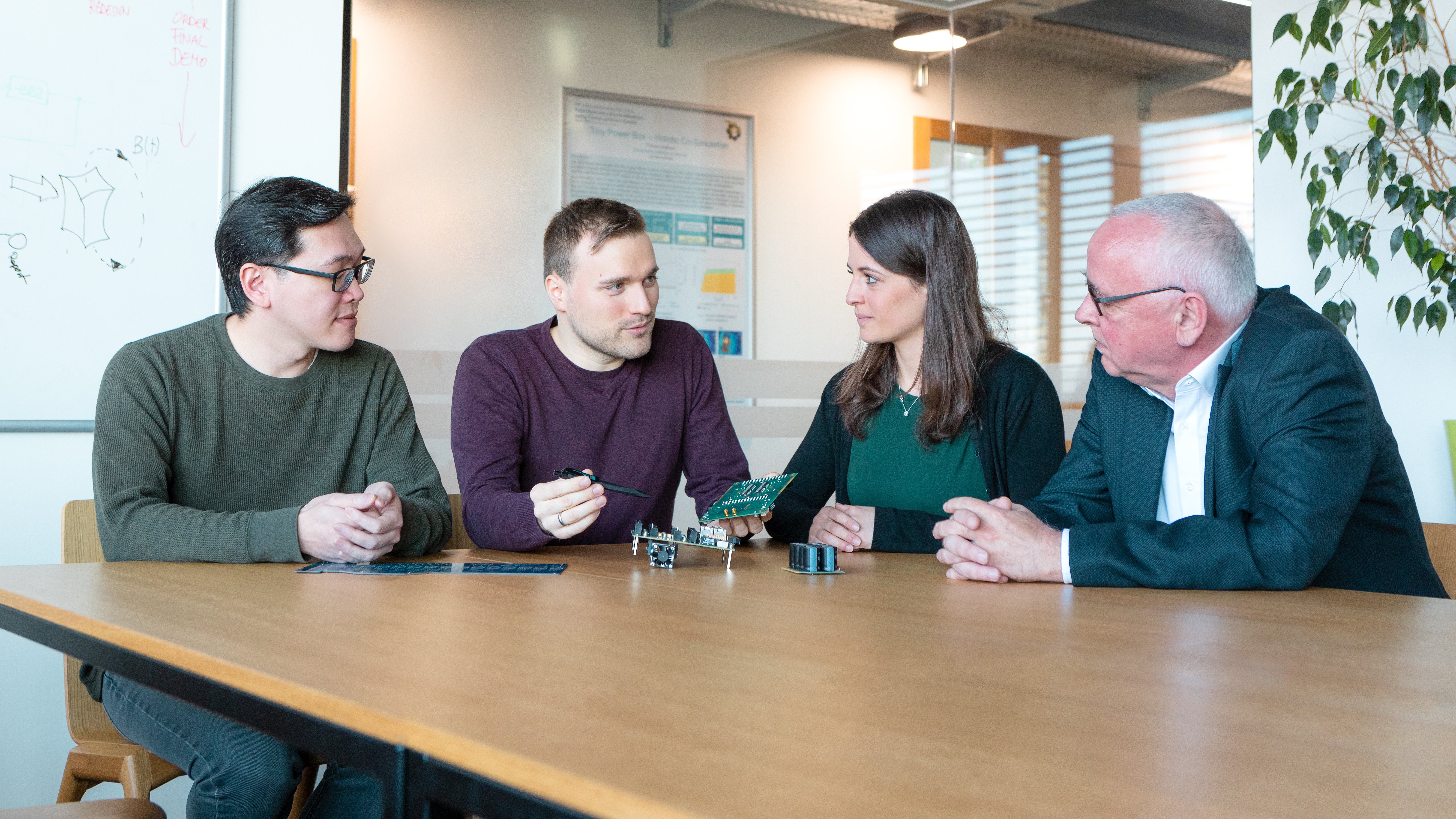 four people sitting at a table in a meeting room