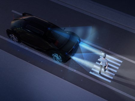 car stopping at a crosswalk at night to let a pedestrian pass