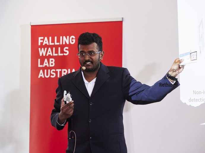 Mani in a suit, presenting at the Falling Walls Lab.