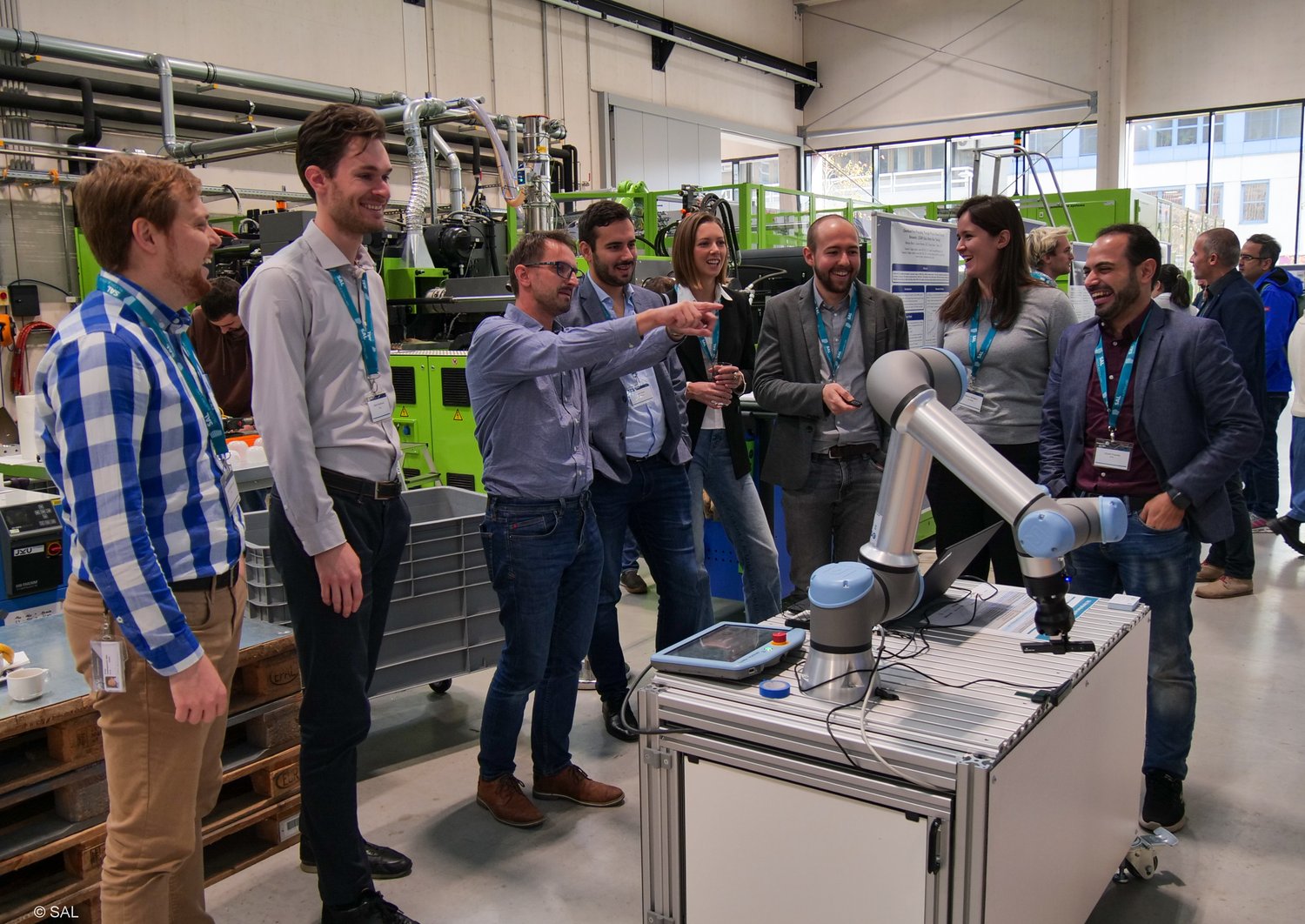 Forscher im Labor vor einem Roboterarm