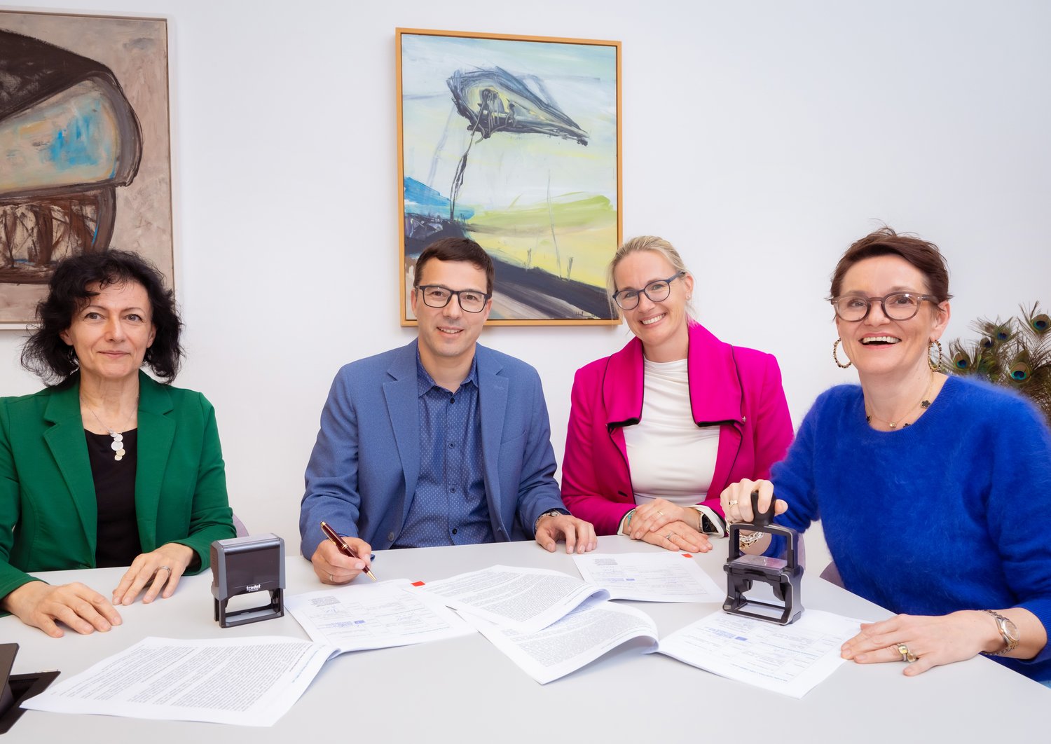 4 people sitting at a table, signed contract in front of them