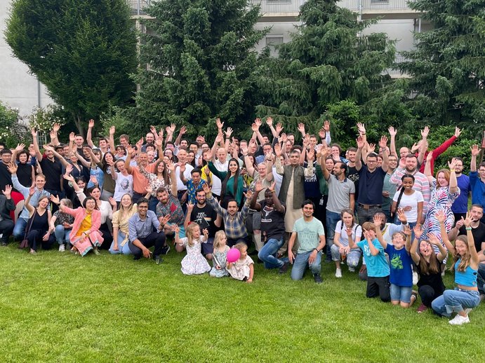 Gruppenbild mit etwa 100 Personen auf einer Wiese