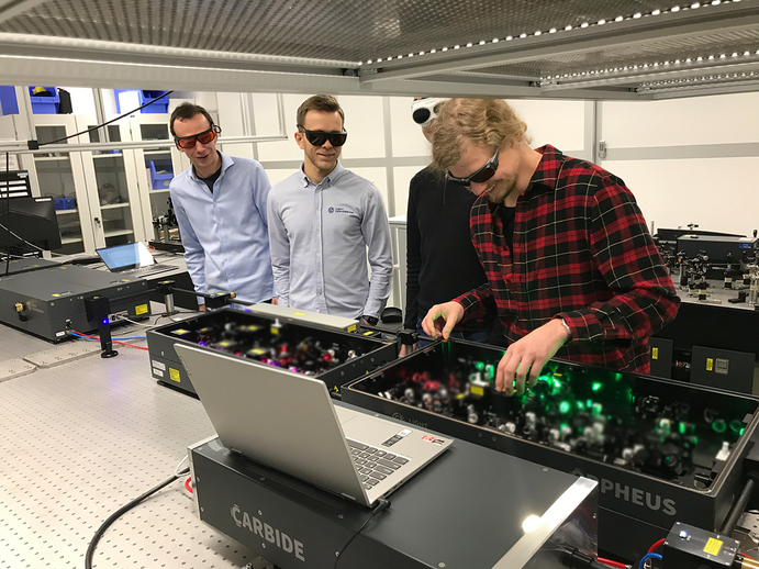 four researchers at the FS Laser System in a lab