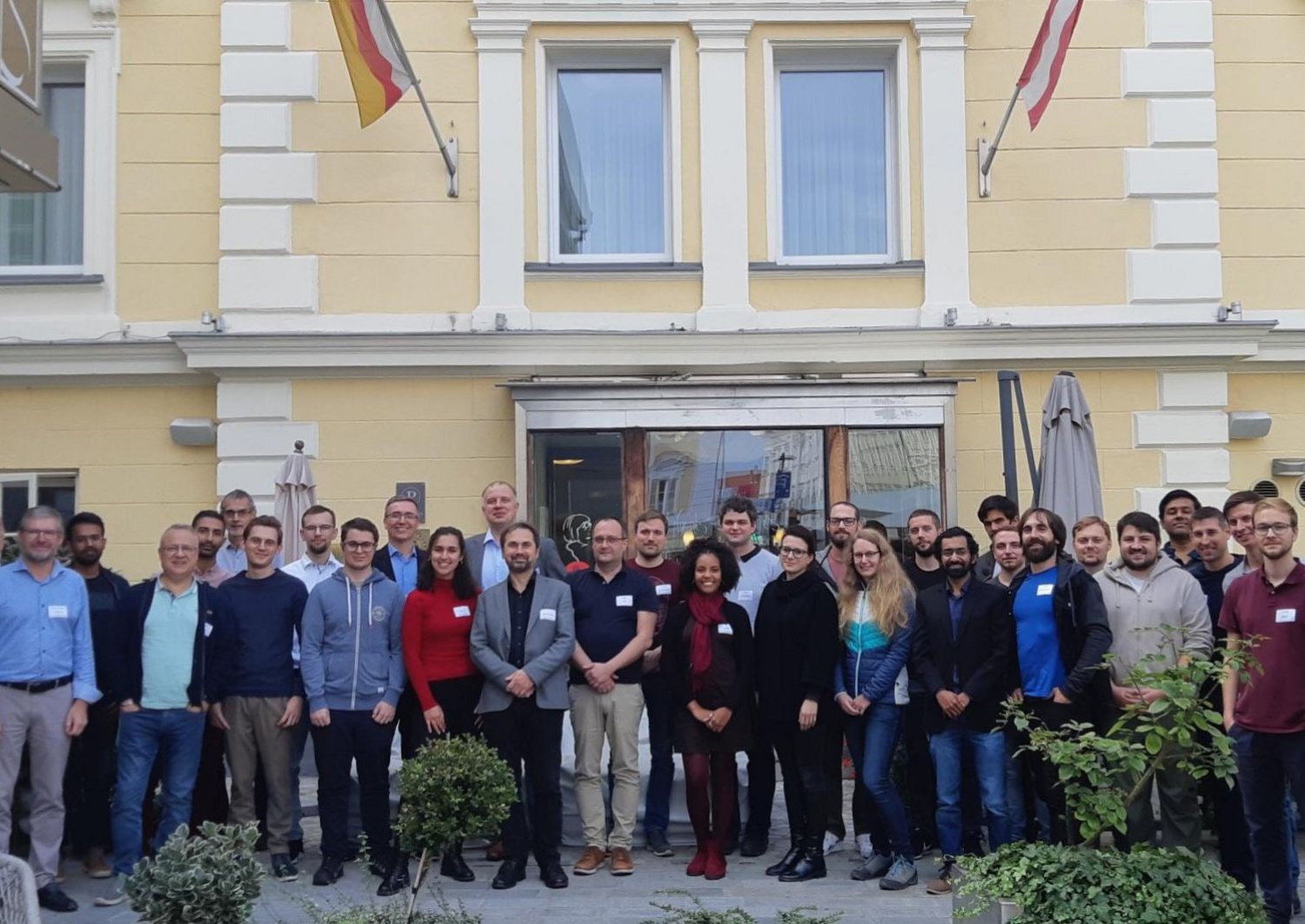 Group picture of students and professors in front of a yellow building