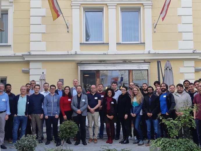 Gruppenfoto von Studiernden und Lehrenden vor einem gelben Gebäude