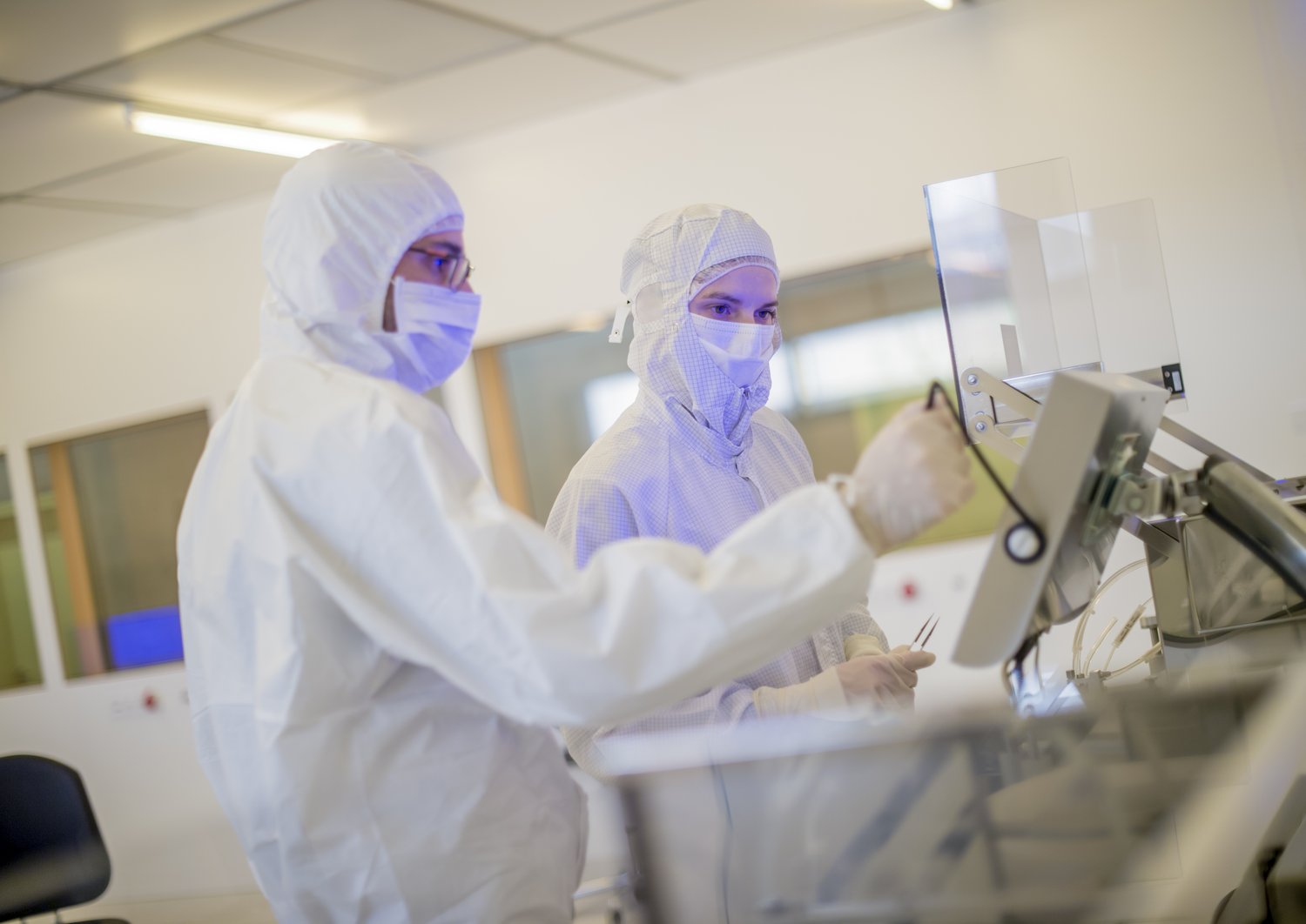 Zwei Personen die an etwas arbeiten in Laboranzügen in einem Reinraum