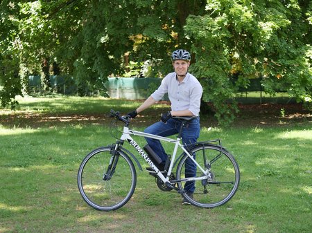 Herbert Hackl in bike clothing, leaning on his bike