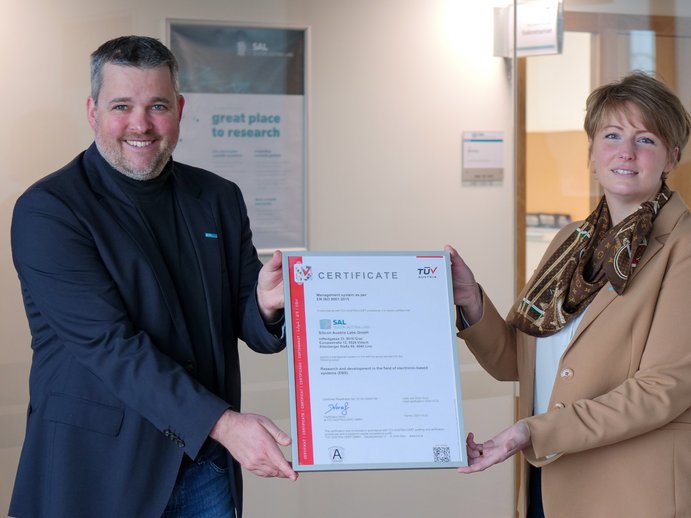 Two people are holding a certificate